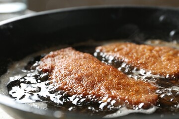 Cooking schnitzels in frying pan, closeup view
