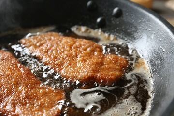 Fototapeta premium Cooking schnitzels in frying pan, closeup view