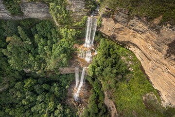 Aerial shot of Katoomba Falls surrounded by green trees on a  sunny day, Blue Mountains, Australia