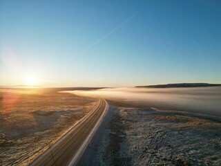 Beautiful view of an empty country road at foggy sunset. Iceland.