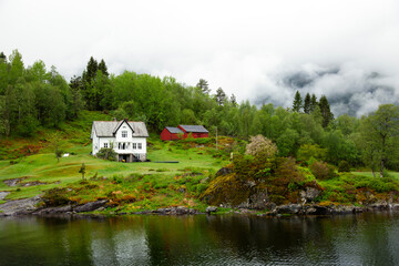 Fototapeta na wymiar Low clouds over houses in the fjord close to Bergen in Norway