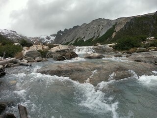 River flowing between rocks and steep mountains on a foggy day