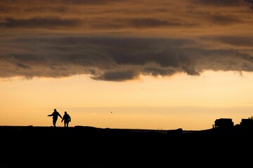Silhouette of two people having fun walking around under a sunset sky
