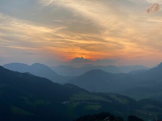 Scenic shot of mountain silhouettes under an orange cloudy sunrise sky