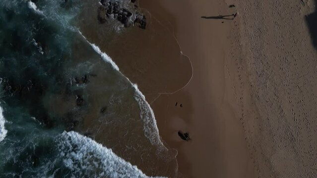 Drone shot over seaside waves in Scottburgh city with green fields and blue sky, South Africa