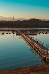 Fototapeta premium Vertical shot of a bridge built on a river against the mountains in the distance