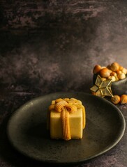 Vertical shot of a hazelnut praline in black plate and small bowl of hazelnuts next to it