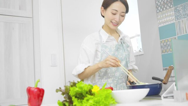 野菜炒めを作る若い女性　料理イメージ