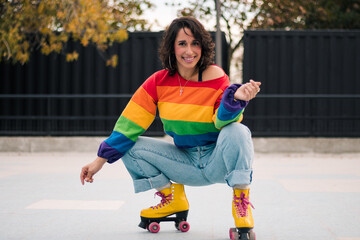bella mujer latina sonriendo, con frenillos, maquillaje y en patines con polera de arcoíris lgbtq en la calle practicando patinaje