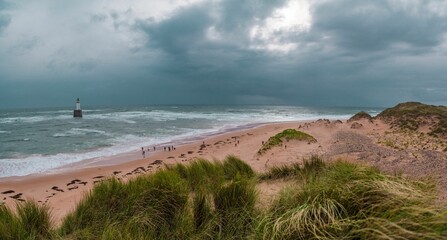 Landscape of the sandy coastline of a stormy sea with the Rattray Head Lighthouse