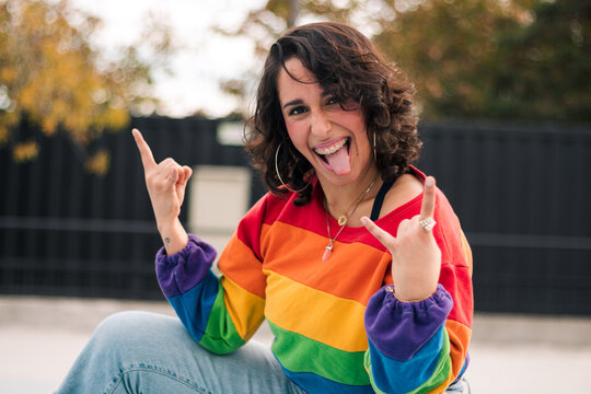 retrato de bella mujer latina sonriendo, con frenillos, maquillaje en patines con polera de arco&iacute;ris lgbtq en la calle practicando patinaje