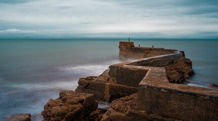 Stone jetty at the shore on the cloudy day