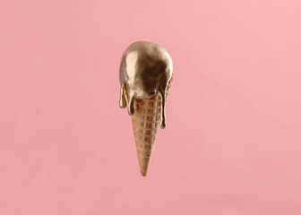 Gold metallic ice cream cone melting isolated on pink background