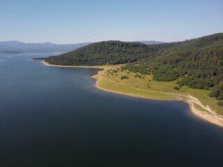 the shore and land next to the water with mountains in the background
