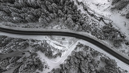 An aerial view of a winding road surrounded by snow-covered trees