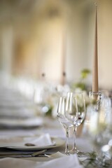 Closeup of a festive table with white dishes and glasses, blurred background