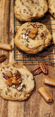 Vertical closeup of chocolate cookies with pecan and caramel on a wooden table