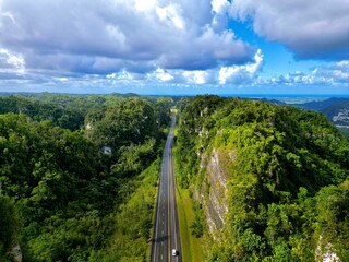 Aerial view of an asphalt road through green forests and mountains in Puerto Rico