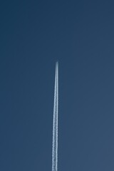 Aircraft soaring through the sky with its white contrails trailing behind it