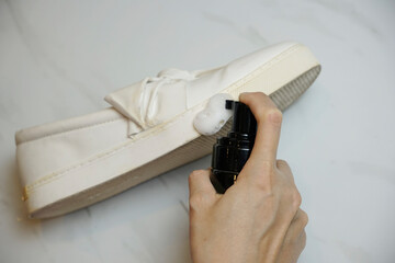 Cropped hand spraying cleaning foam on a sneaker base