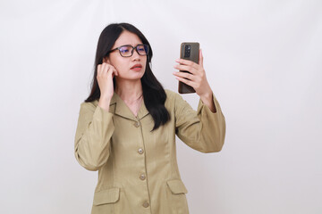 Confused young indonesian government worker standing while holding cell phone