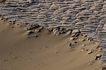 Scenic beachscape featuring an impressive wave-like formation made of sand and rocks