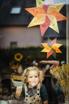 Girl holding sandwich looking out of the window with kite paper stars