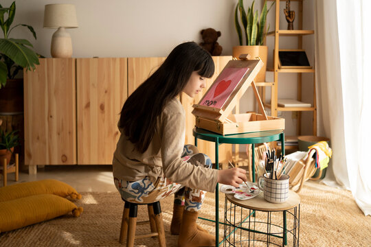 Beautiful girl painting heart at home
