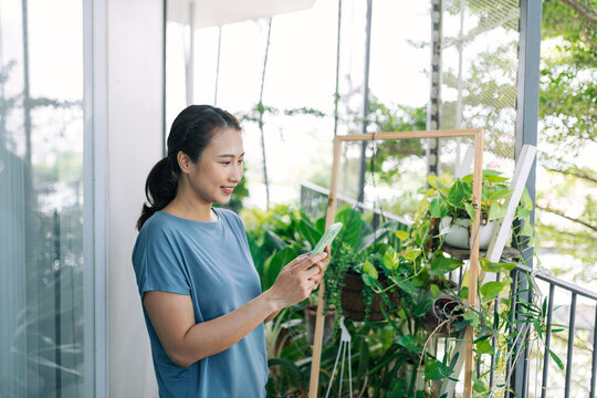 Young woman taking care of her herbs and taking picture of it