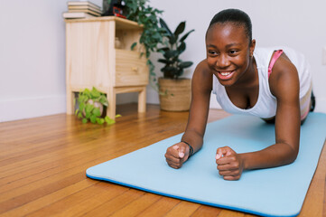 smiling black teen doing plank on yoga mat