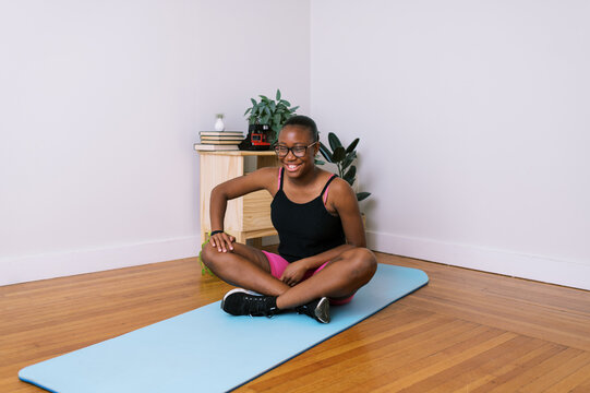 Smiling black tween girl on yoga mat at home