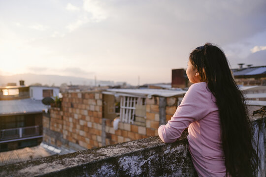 Woman leaning on rooftop wall admiring The view