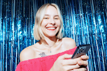 Young Woman With Phone Typing At A Party