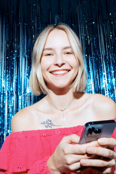 Young Woman With Phone Smiling On Blue Party Background