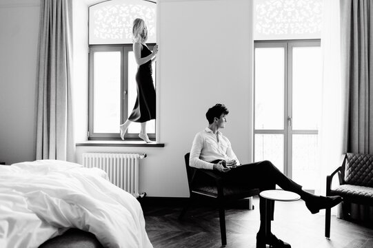 Slim woman standing on windowsill near cheerful boyfriend
