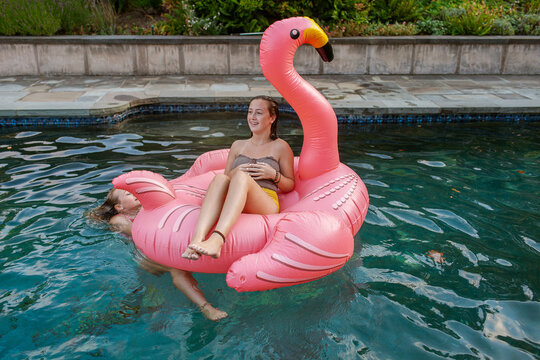 Teen girls having fun with flamingo float at pool party