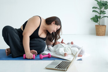 Chubby mom in sportswear pause  her online fitness class on laptop and teasing her baby, doing...