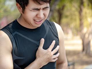 Severe heartache. Athlete man clutching his chest from acute pain suffering from heart attack while...