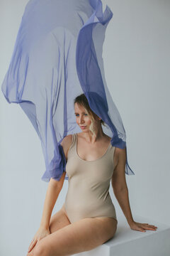 Attractive real body type woman sitting on cube and looking away 