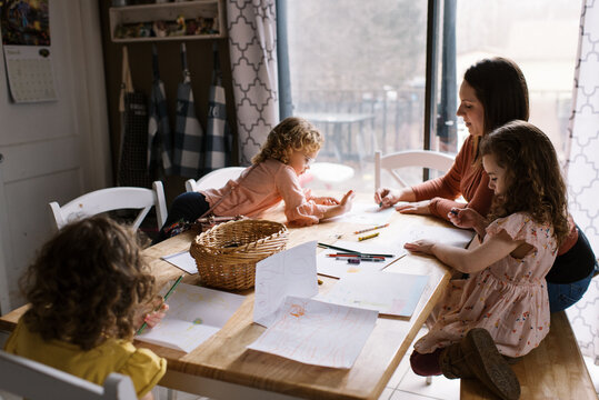 Naklejki Kids drawing at home at kitchen table together with their mother