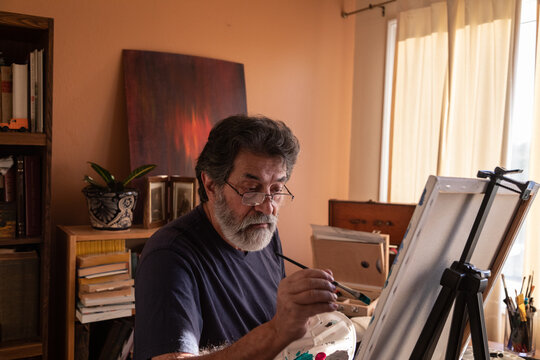 Retired latin man painting at home