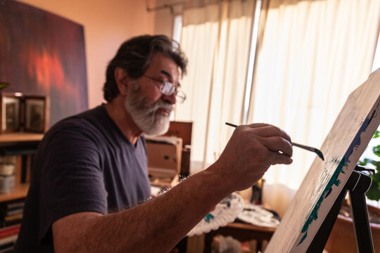 Retired latin man painting at home