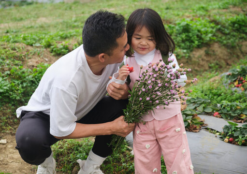 Love interaction of Asian father and daughter holding fresh flower