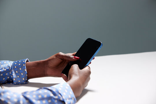 Unrecognizable black woman using smartphone at table