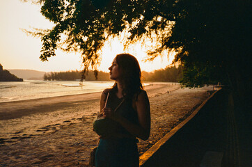Woman with coconut on the beach at sunset 