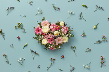 Heart-shaped bouquet in box with scattered flowers.
