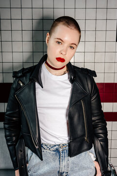 Portrait of millennial female on tile wall background, direct flash