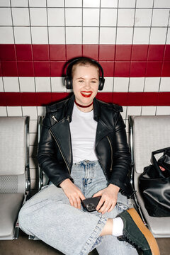 Smiling happy woman in headphones in subway, direct flash