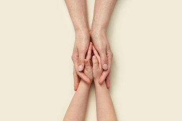 Supporting mother's hands holding little kid's hands.