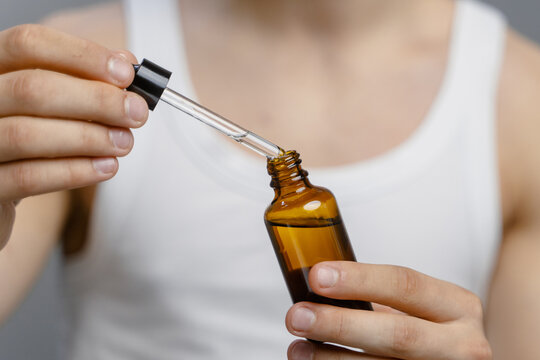 A bottle with a pipette in women's hands